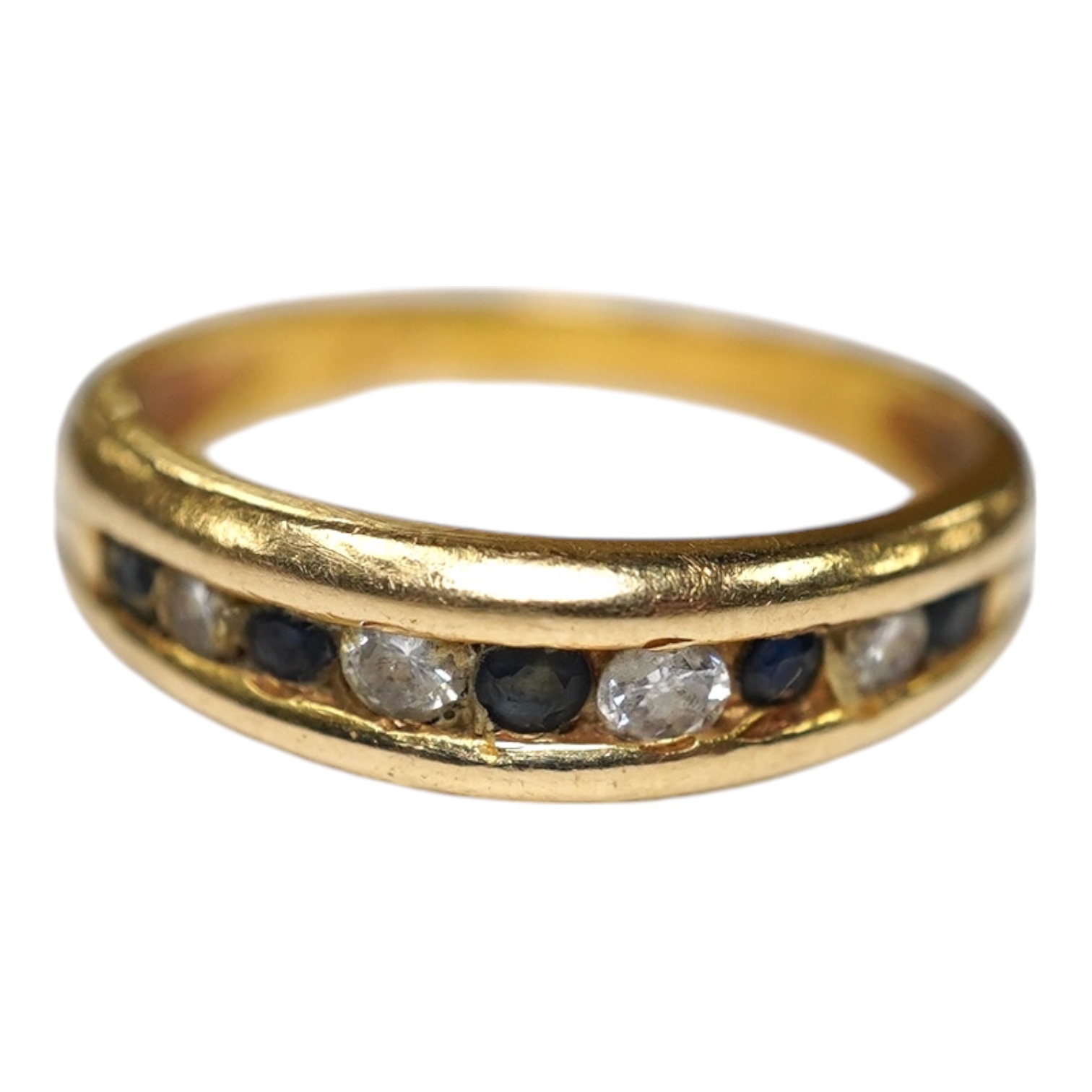 A yellow metal and channel set sapphire and diamond set half hoop ring, size Q/R, gross weight 4.2 grams. Condition - fair